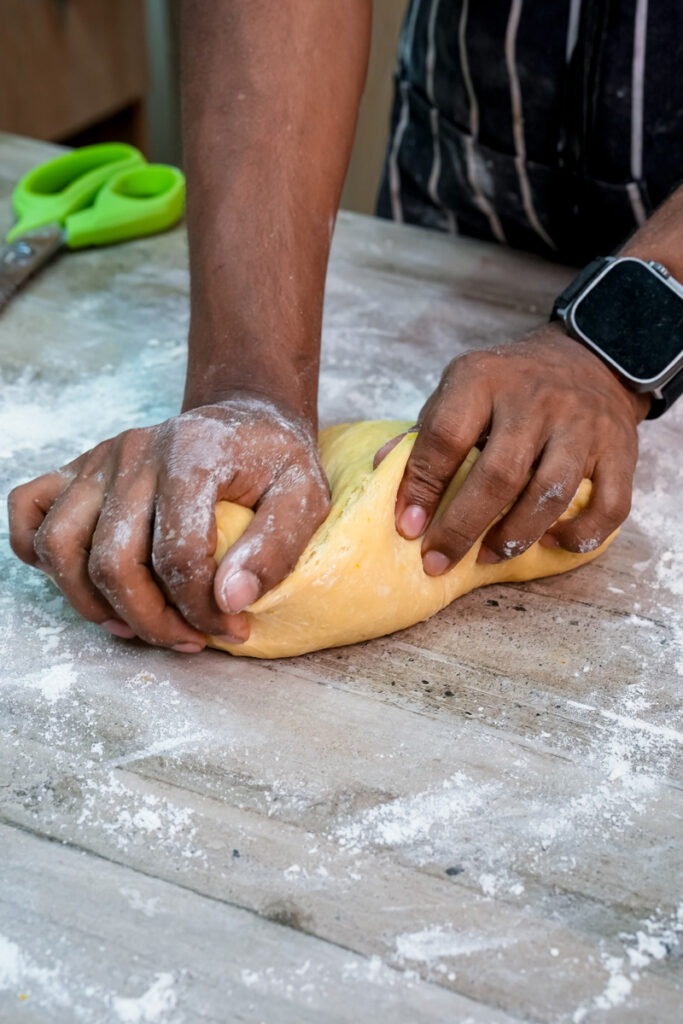 Kneading pan de muerto dough by hand on floured surface