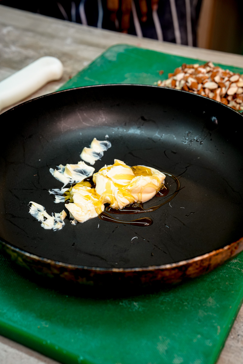 Melting butter in black skillet for bee sting cake honey almond topping