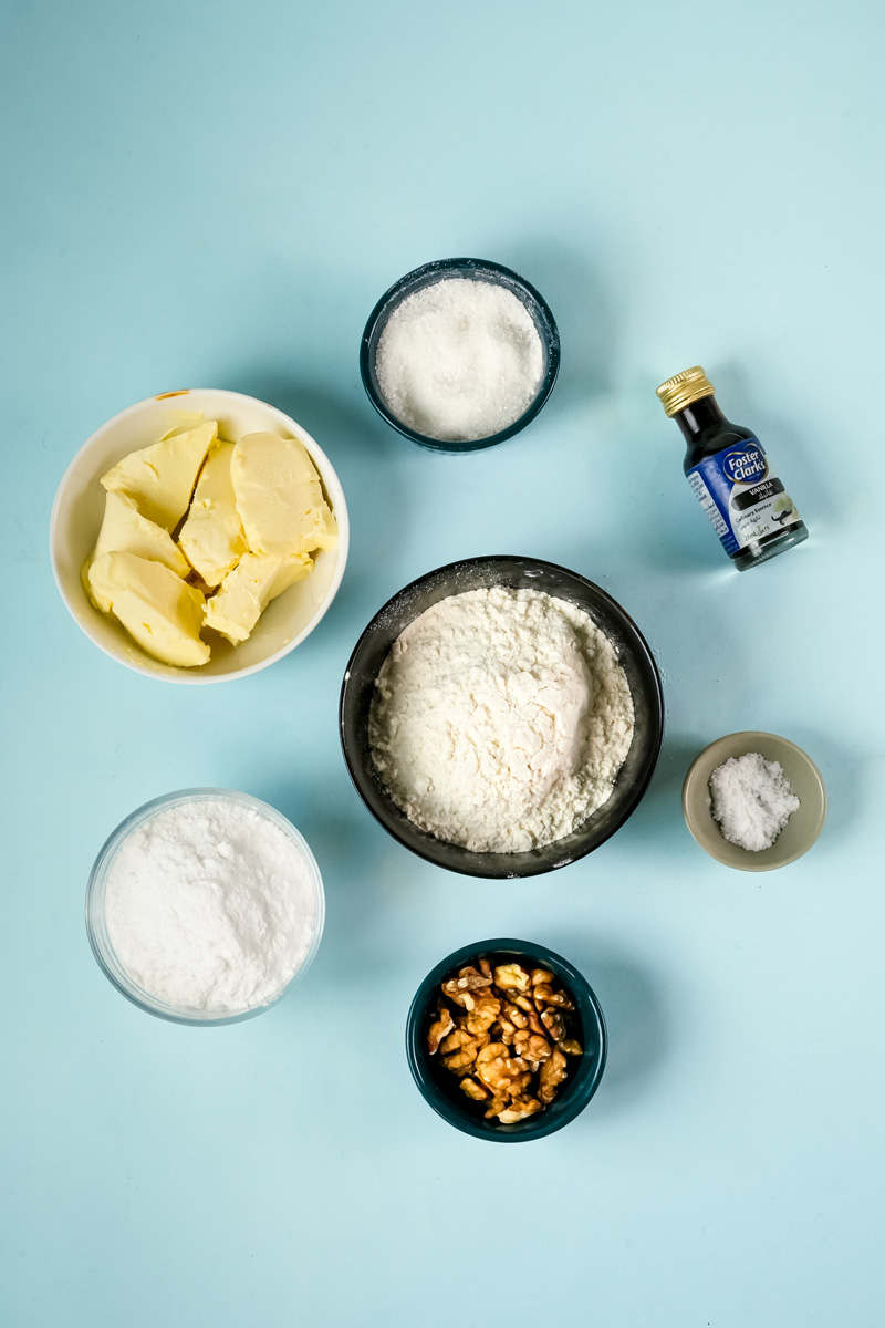 Mexican wedding cookie ingredients - butter, powdered sugar, flour, vanilla, salt, and chopped walnuts