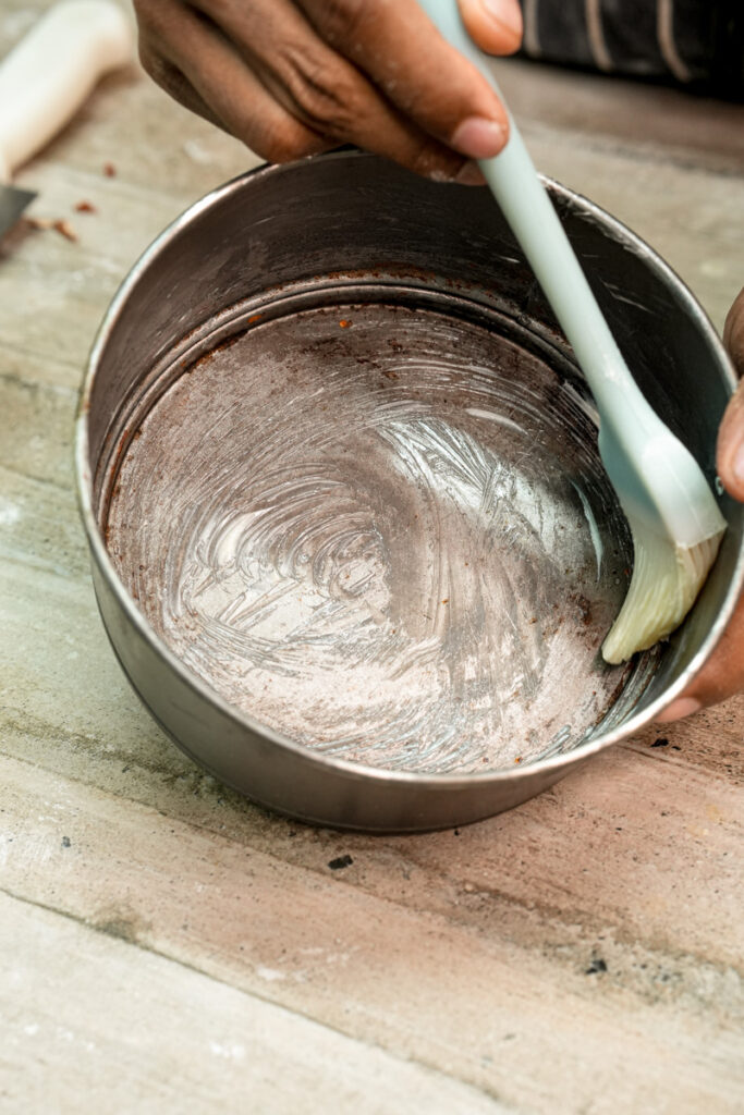 Mixing bee sting cake batter in metal bowl with rubber spatula
