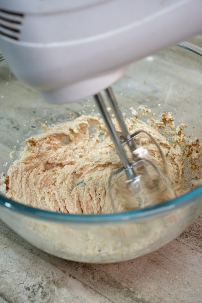 Mixing butter sugar mixture with electric hand mixer