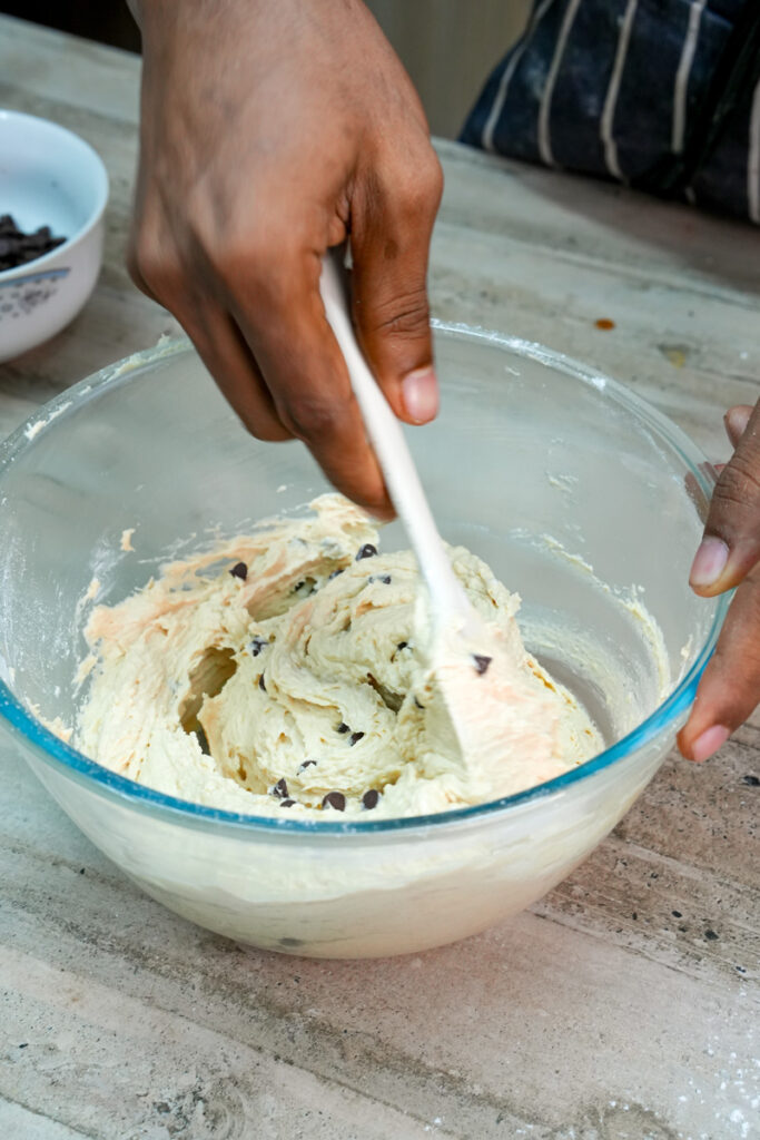 Mixing chocolate chips into cookie dough with a spatula
