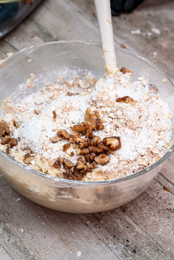 Mixing chopped walnuts and flour into cookie dough
