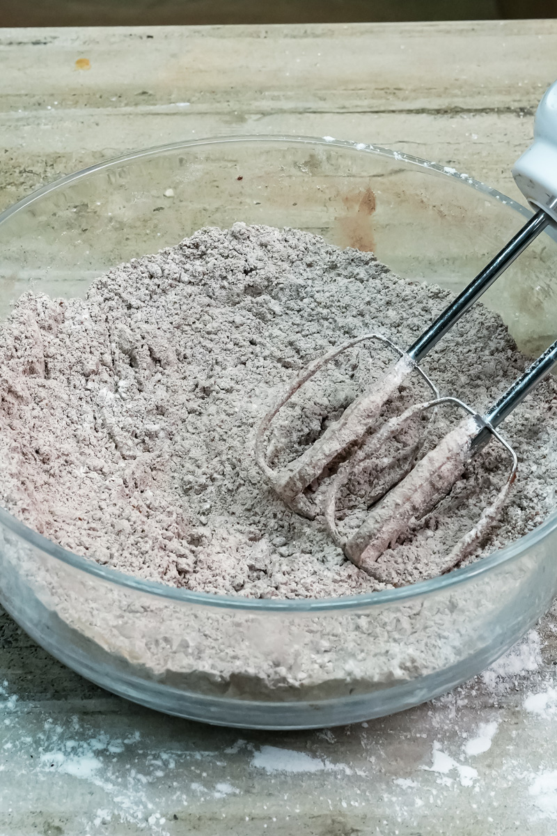 Mixing dry ingredients for Oreo cookie dough in a glass bowl with a mixer
