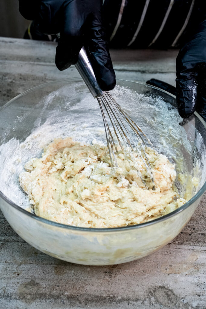 Mixing the dry and wet ingredients for banana protein muffins with a wire whiskMixing the dry and wet ingredients for banana protein muffins with a wire whisk