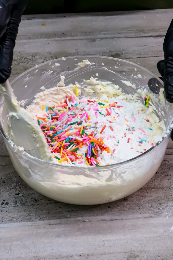 Mixing the dry ingredients and sprinkles into the wet mixture to form a dough