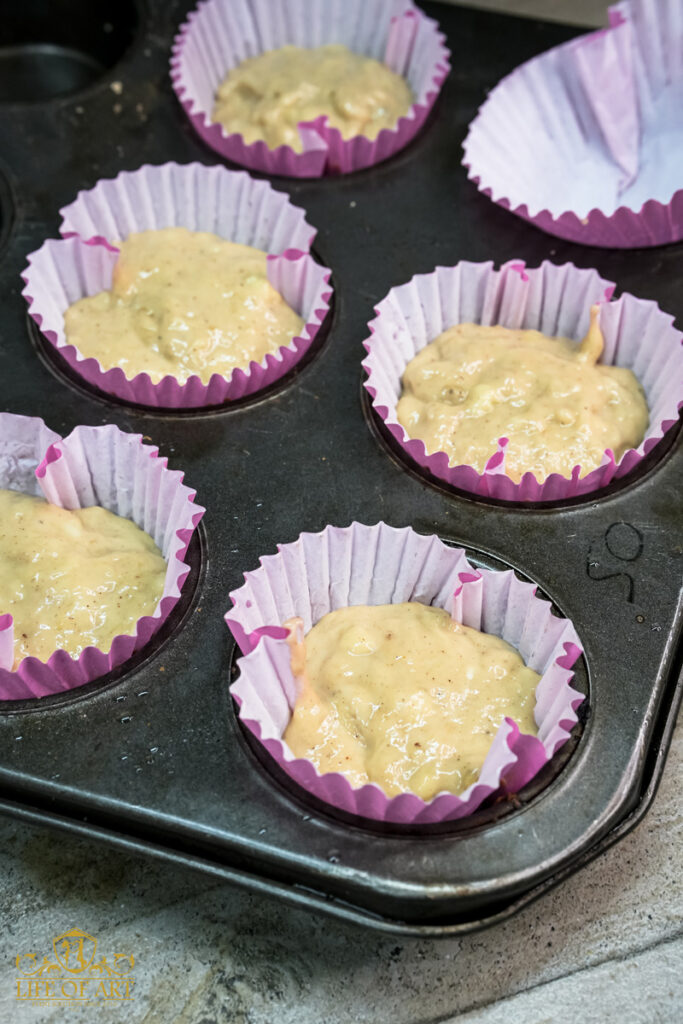 Muffin tin with liners filled with raw banana muffin batter