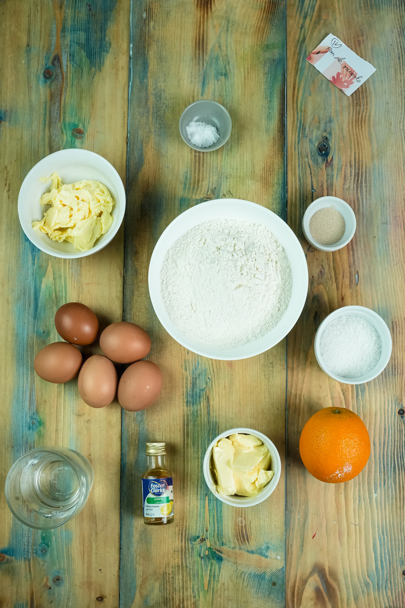 Pan de Muerto ingredients laid out including flour, eggs, butter, orange, and yeast for baking