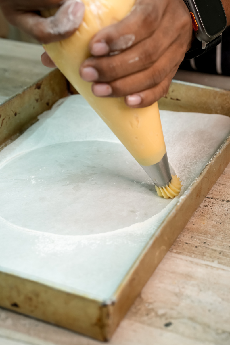 Piping choux pastry dough in circular pattern for Paris Brest