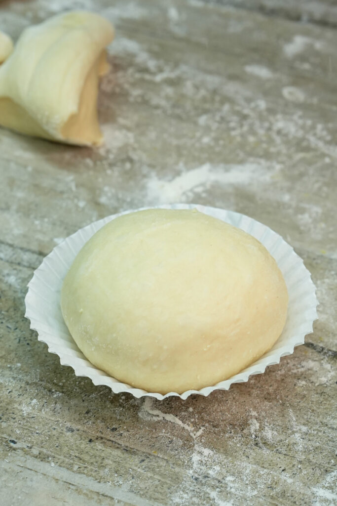 Placing shaped dough in paper liner for baking