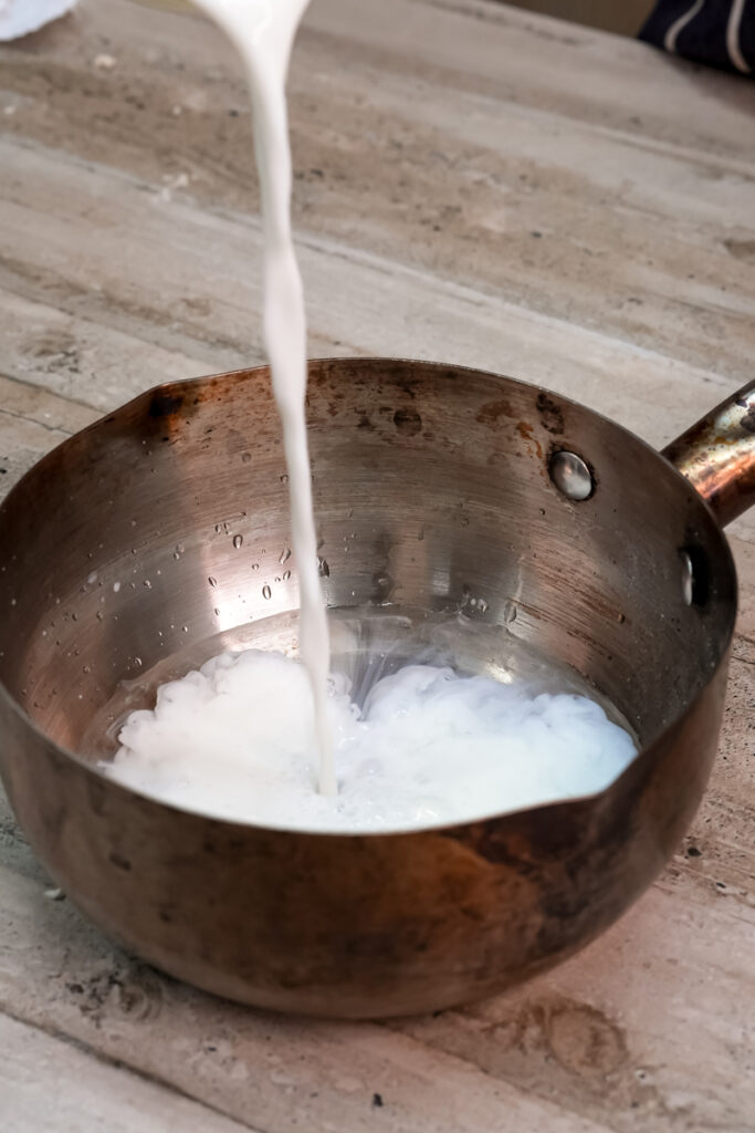 Pouring milk into saucepan for pastry cream preparation