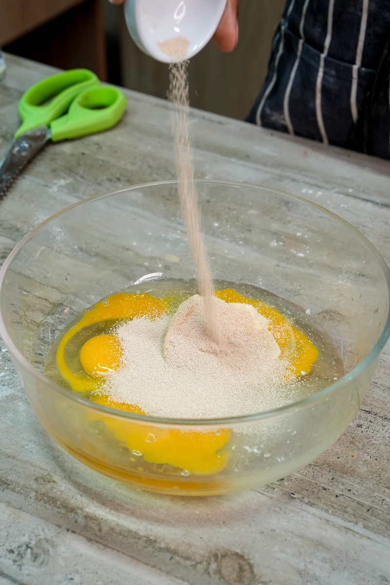 Pouring sugar into egg mixture for pan de muerto