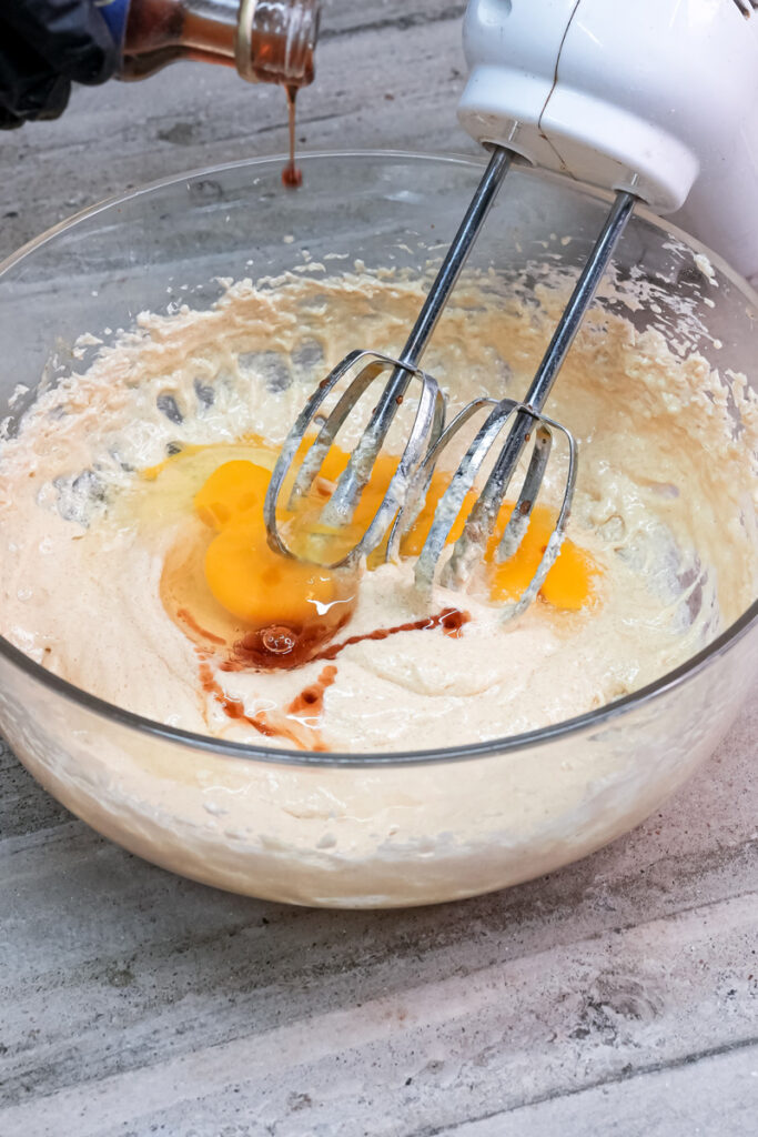 Pouring vanilla extract into ranger cookie batter with mixer beaters