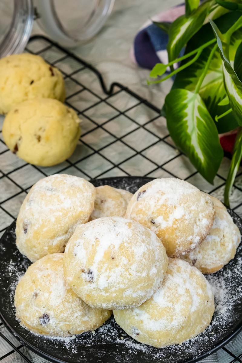 Powdered sugar coated Mexican wedding cookies on dark serving plate