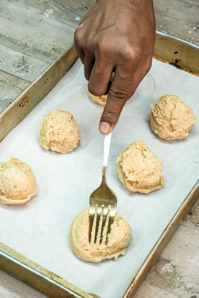 Pressing down cookie dough with a fork before baking