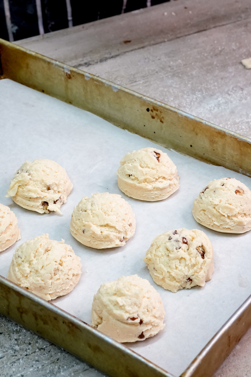Raw Mexican wedding cookie dough balls on parchment-lined baking sheet