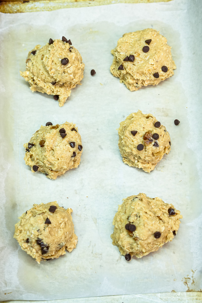 Raw cowboy cookie dough balls on parchment paper before baking