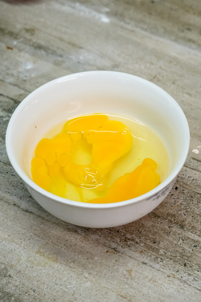 Raw eggs in white bowl for oatmeal raisin cookies