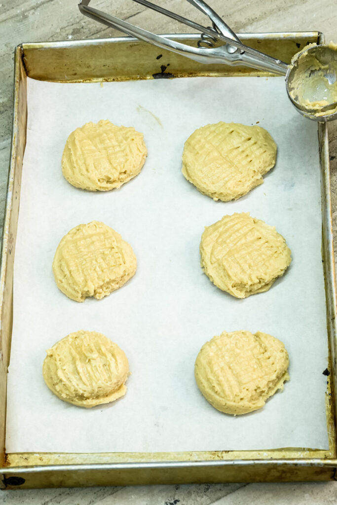 Raw peanut butter cookies with classic fork marks on a tray
