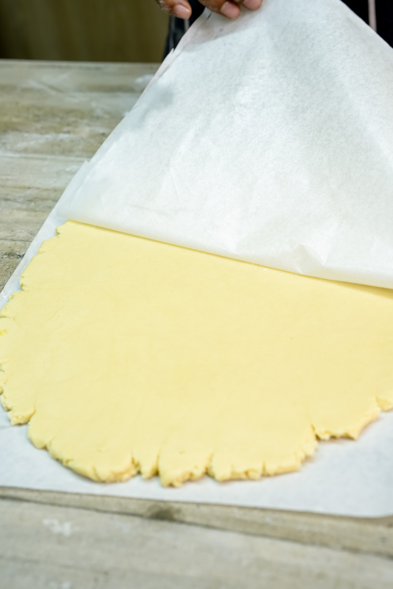 Rolling alfajores cookie dough between parchment paper