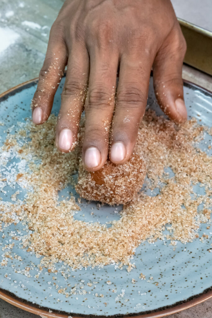 Rolling molasses cookie dough in granulated sugar coating