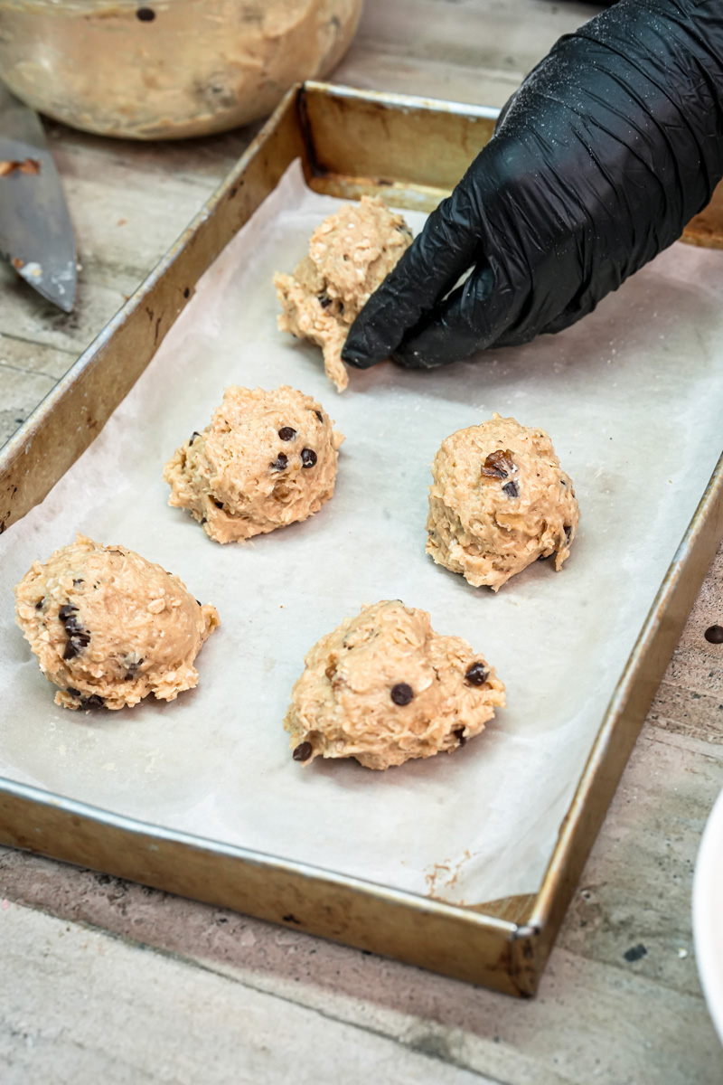 Scooping cowboy cookie dough onto parchment-lined baking sheet
