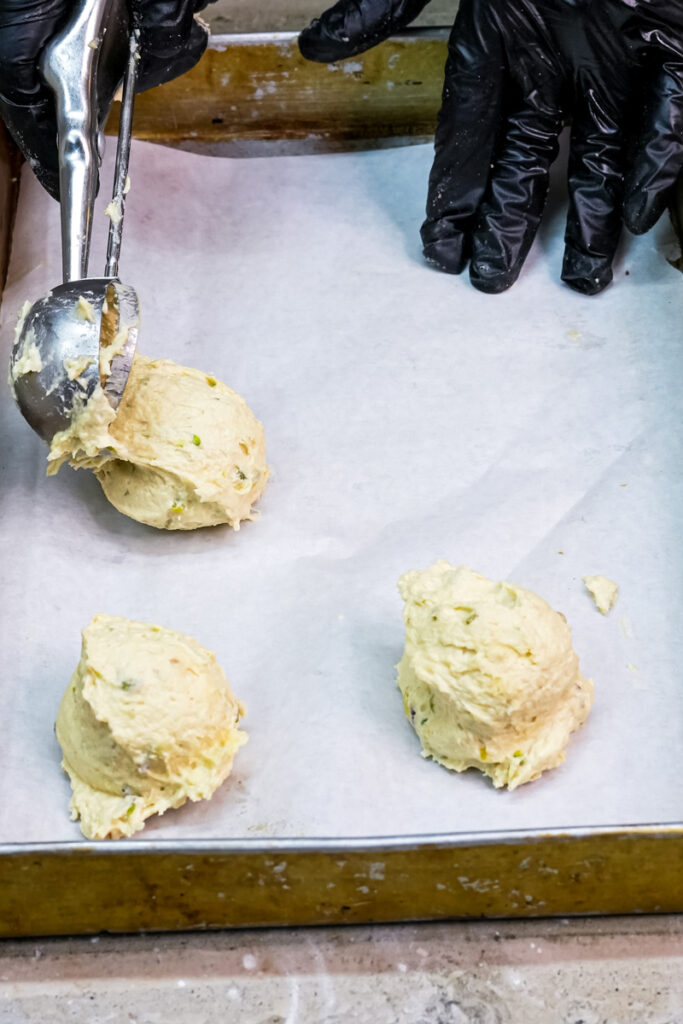 Scooping portions of pistachio cookie dough onto a baking sheet