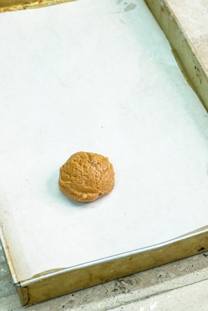Single molasses cookie dough ball on parchment paper