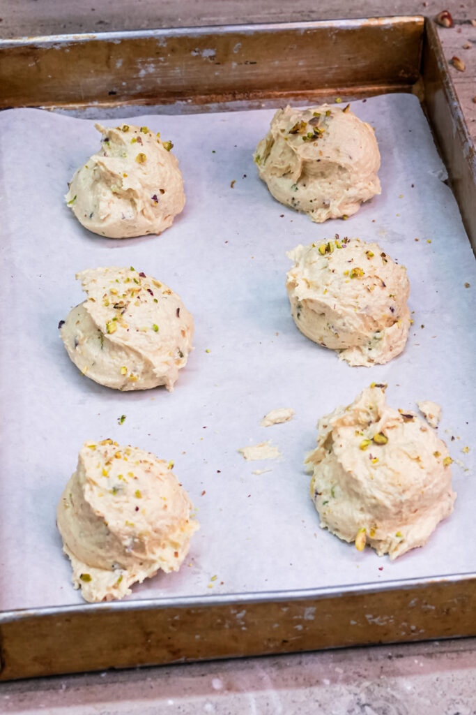 Six scoops of pistachio cookie dough on a baking sheet lined with parchment paper