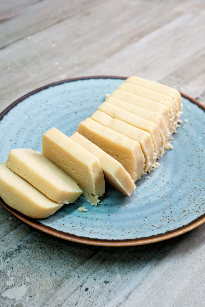 Sliced shortbread cookie dough arranged on ceramic plate ready for baking
