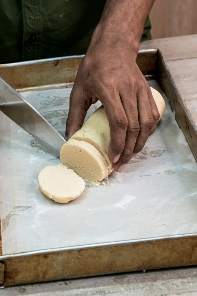 Slicing Twix cookie dough log with knife on cutting board