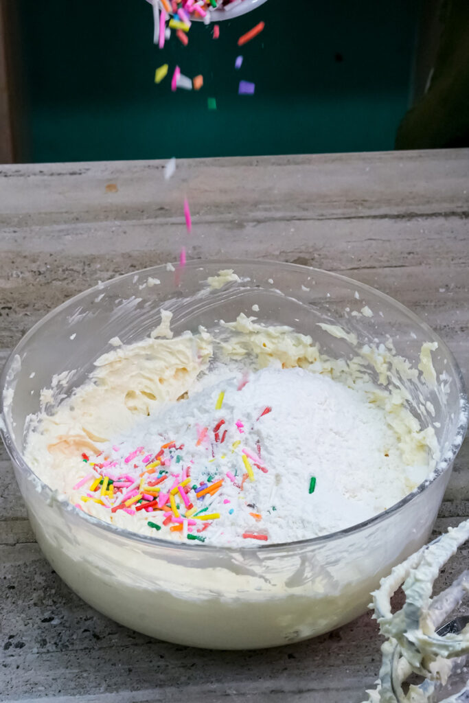 Sprinkles being poured into the cookie dough mixture