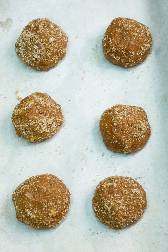 Sugar-coated molasses cookie dough balls on baking sheet