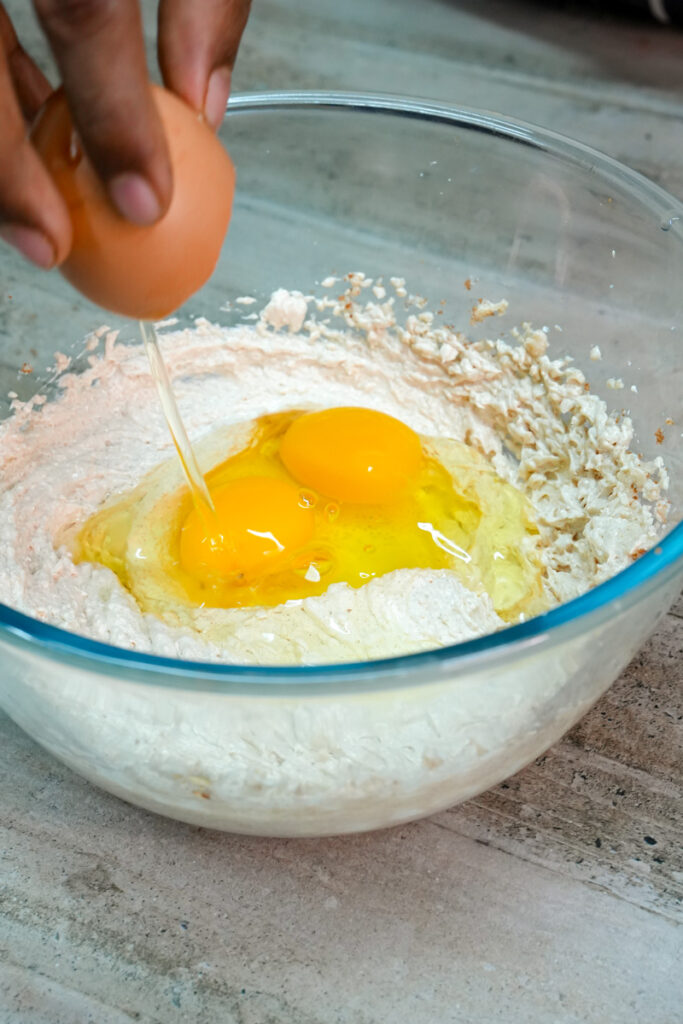 Two eggs cracked into the cookie dough mixture