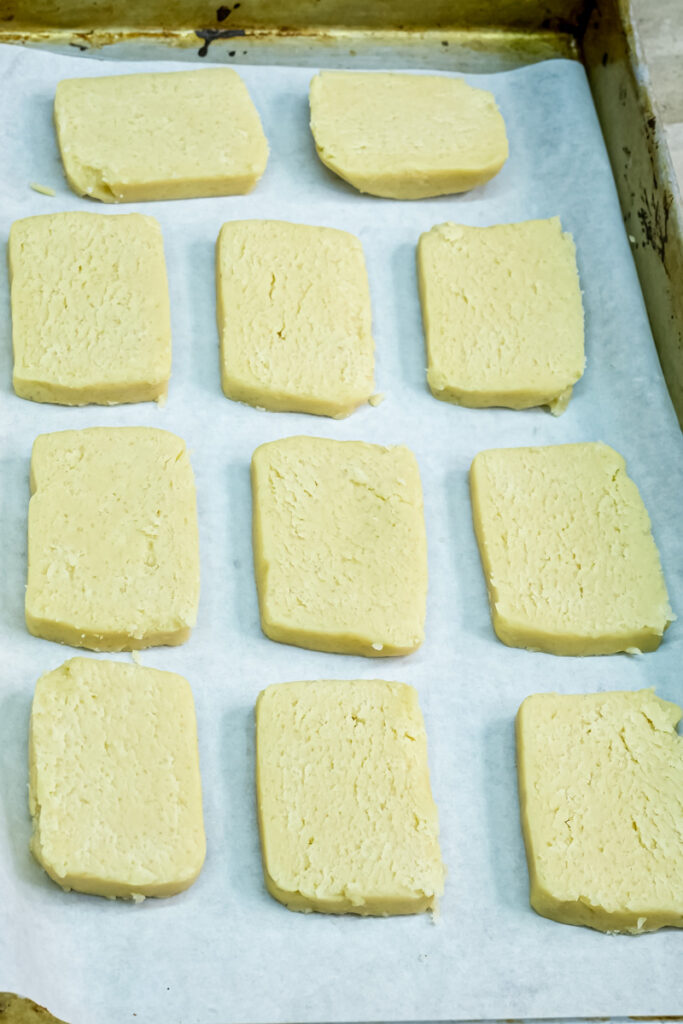 Unbaked shortbread cookies arranged on baking tray with parchment paper