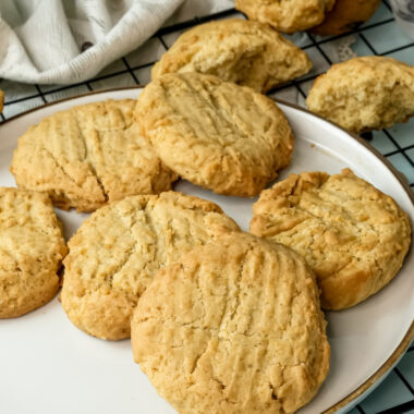 Warm peanut butter cookies displayed on a plate and cooling rack