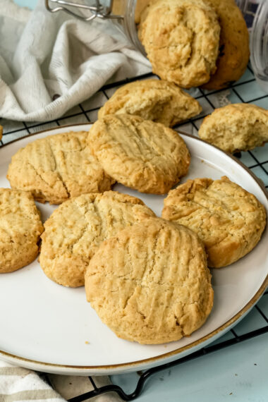 Warm peanut butter cookies displayed on a plate and cooling rack
