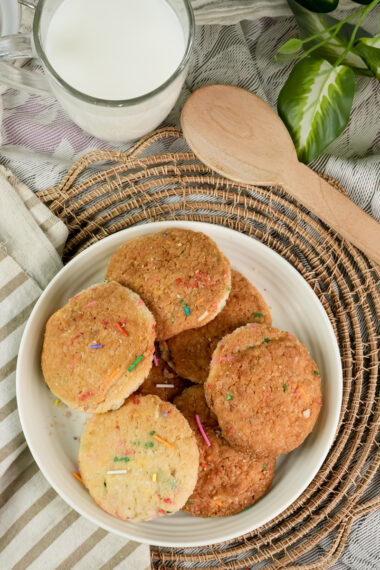 A top-down view of a plate of Funfetti cookies with a glass of milk