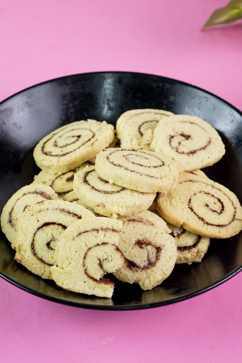 A black bowl filled with baked cinnamon roll cookies