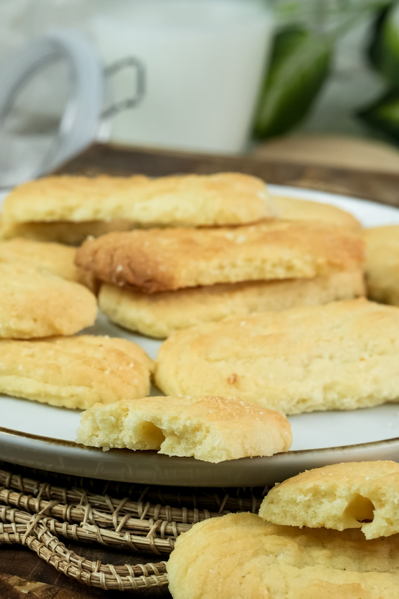 A close-up of a broken spritz cookie on a plate, revealing its soft, crumbly texture