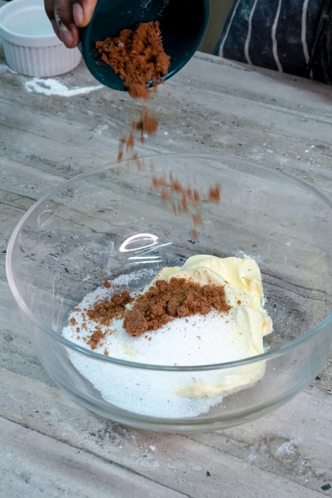 Pouring brown sugar into butter and sugar mix