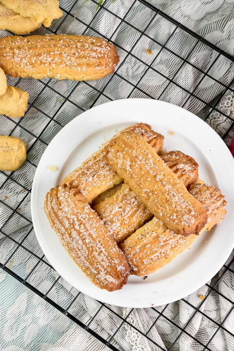 Delicious churro cookies on a white plate and a cooling rack, ready to be eaten