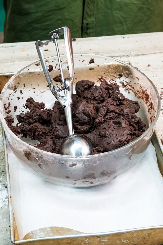 A cookie scoop in a bowl of chocolate Oreo cookie dough