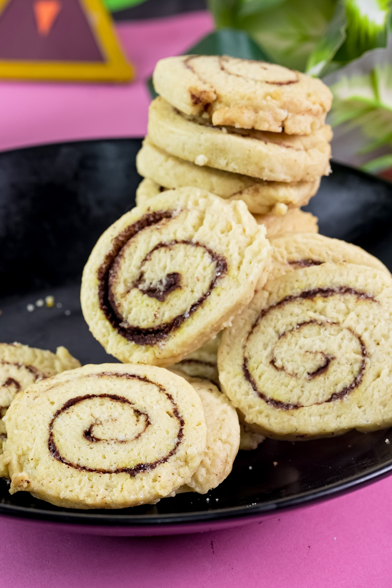 A close-up of delicious baked cinnamon roll cookies on a black plate