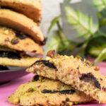 A close-up of two fresh-baked pistachio cookies, one broken open