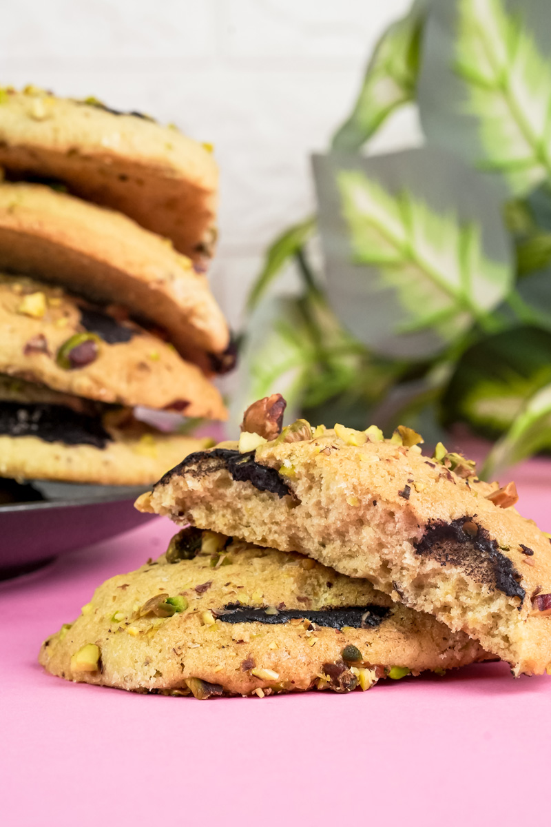 A close-up of two fresh-baked pistachio cookies, one broken open