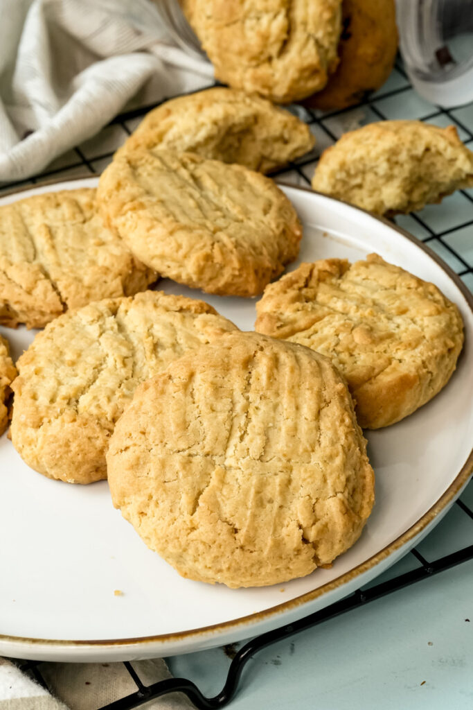 A plate of fresh peanut butter cookies next to a cooling rack