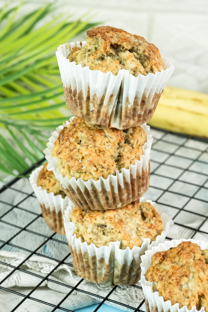 Stack of three freshly baked banana protein muffins on a wire cooling rack