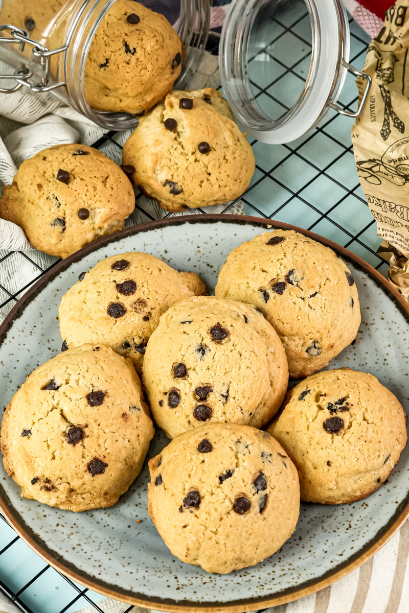 Freshly baked chocolate chip cookies on a plate and cooling rack