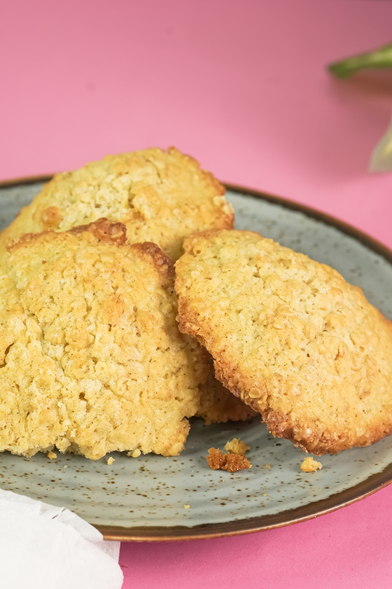 A side view of three freshly baked oatmeal cookies stacked on a grey plate